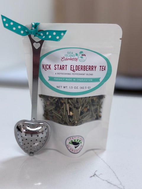 Packaged elderberry tea with a heart-shaped tea infuser on a white surface made in Charleston SC.