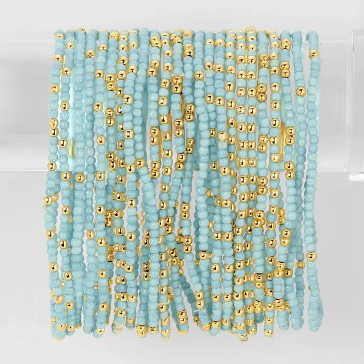 Turquoise and gold beaded strands on a white background