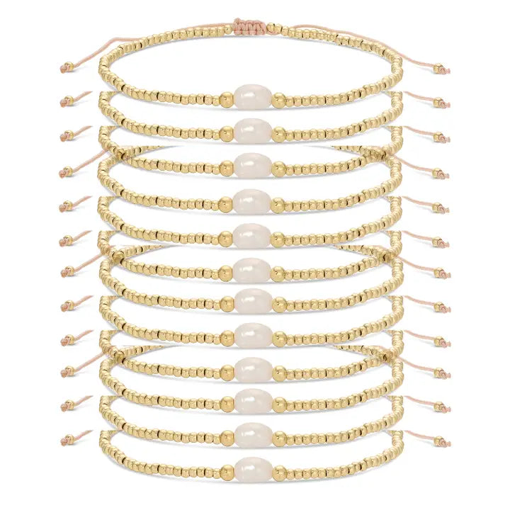 Set of gold beaded bracelets with pearls on a white background