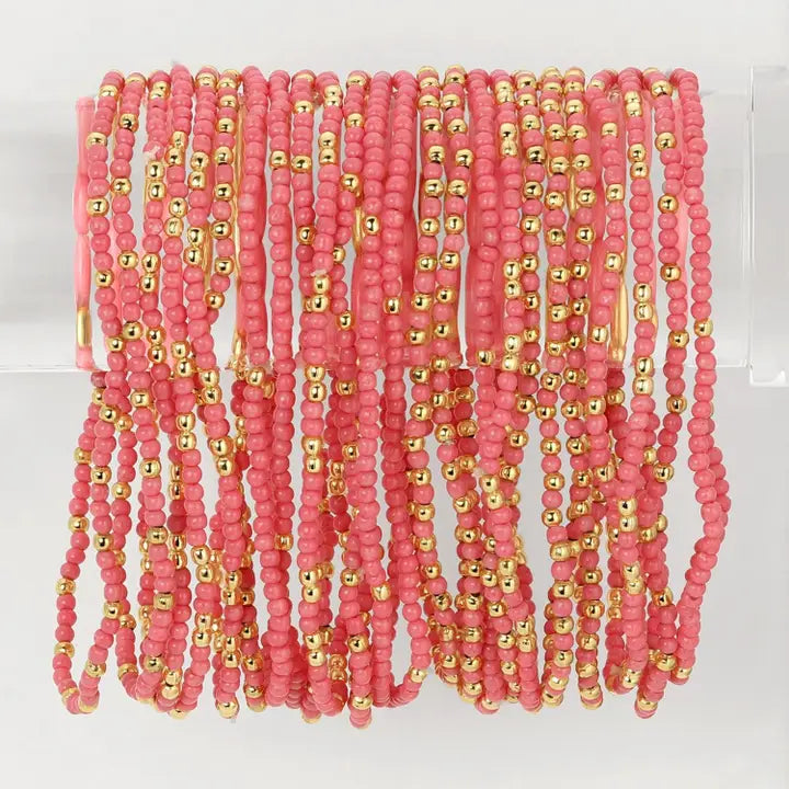 Multiple pink beaded necklaces with gold accents on a white background