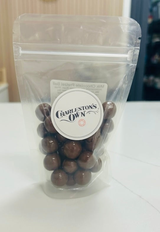 Clear plastic bag with chocolate balls and a label on a white surface. Locally made in Charleston 