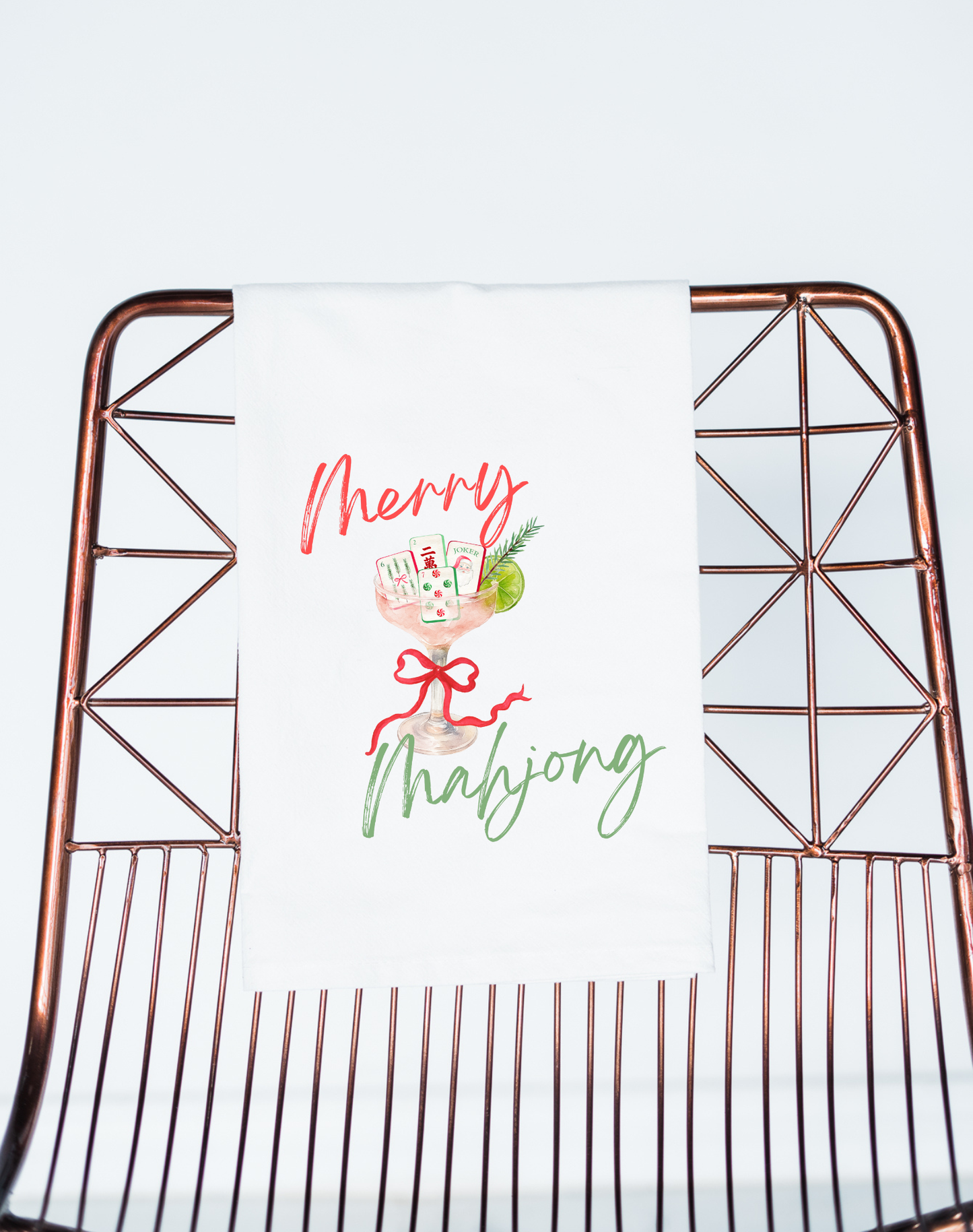 Decorative towel with 'Merry Mahjong' text on a metal chair