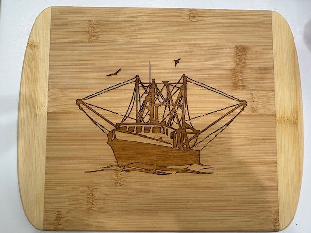 Wooden cutting board with a engraved ship design on a white background