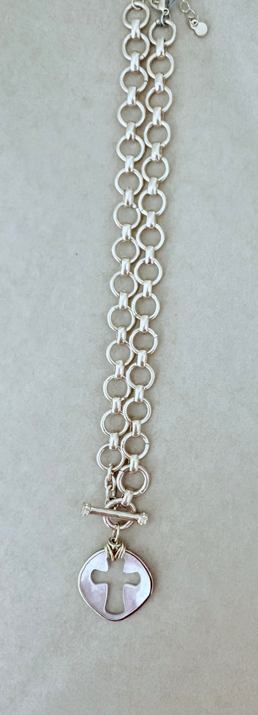 Silver bracelet with a cross charm on a light gray background ~ local Charleston jewelry