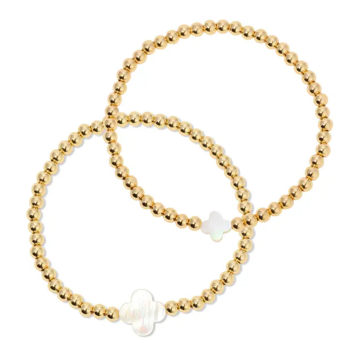 Gold beaded bracelet with a white bead on a white background