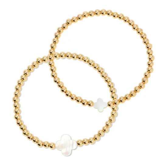 Gold beaded bracelet with a white bead on a white background